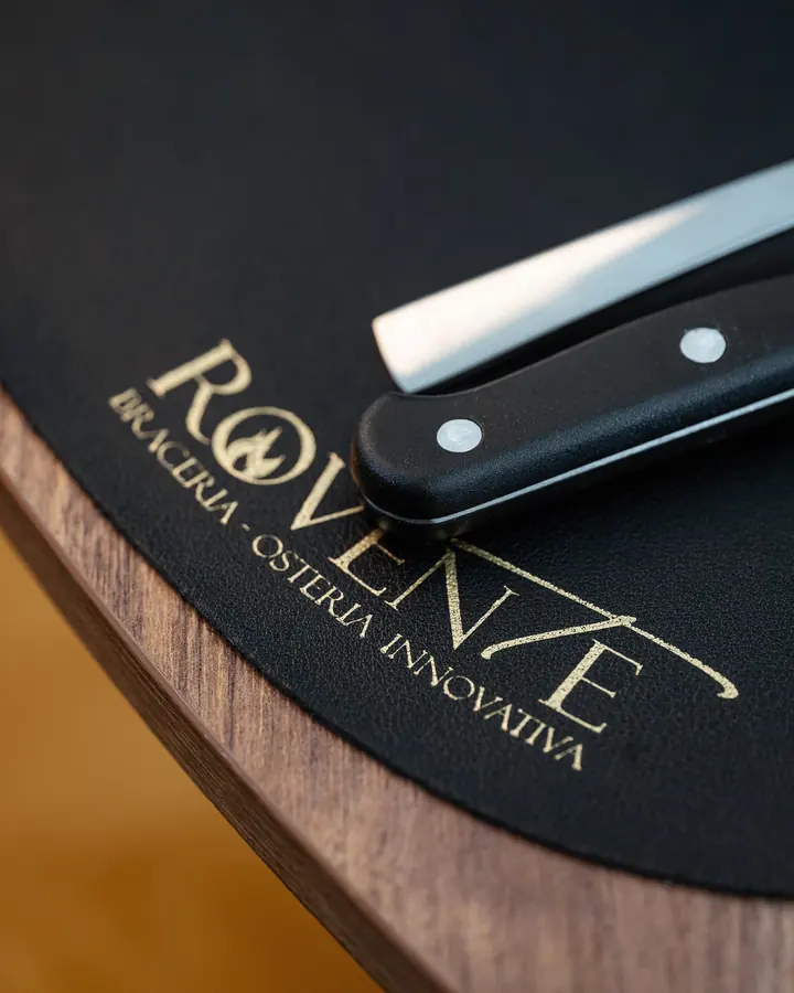 Il logo Rovente in oro su un tagliere nero con un coltello