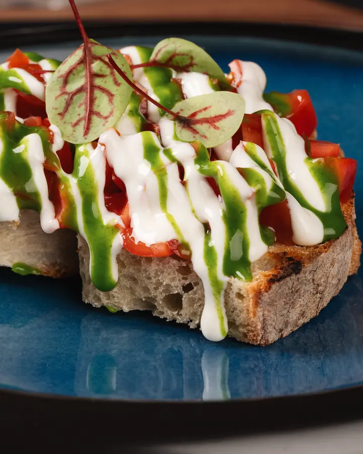 Crostone di pane con pomodoro, crema bianca e salsa verde