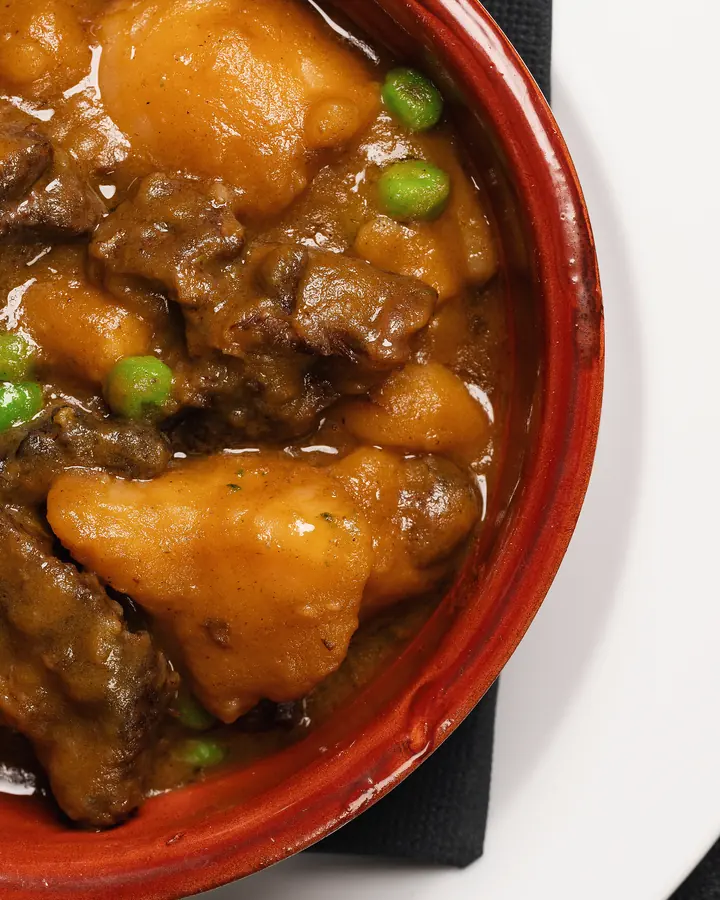 Spezzatino con patate e piselli in una ciotola rossa