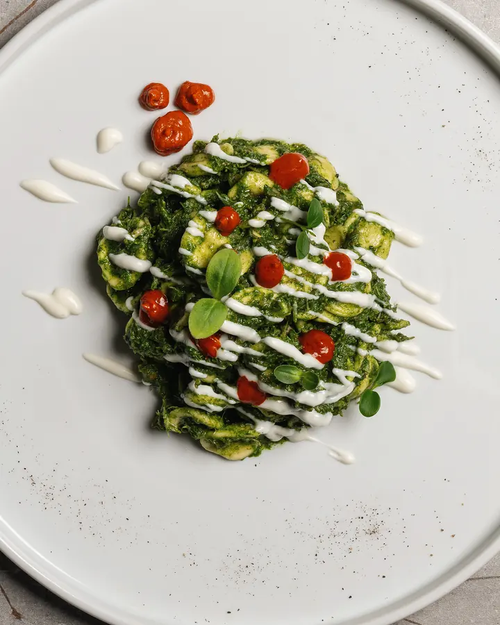 Verdure con pomodorini e crema bianca su un piatto bianco