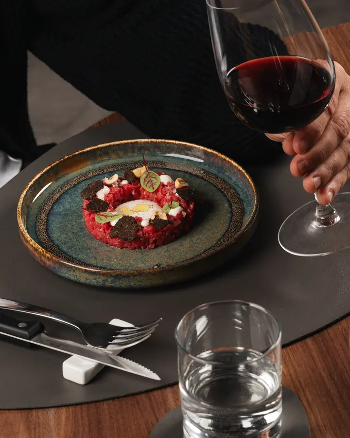 Tartare servita al tavolo con un calice di vino rosso